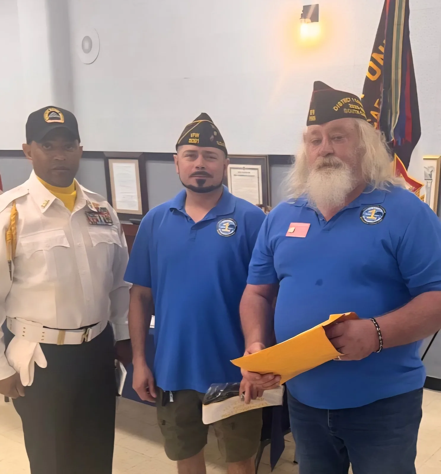 Three people together at the post, two wearing VFW caps